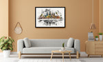 A framed watercolor painting of Angkor Wat and the surrounding temples in Cambodia, displayed on a warm beige wall above a modern light gray sofa in a styled living room.
