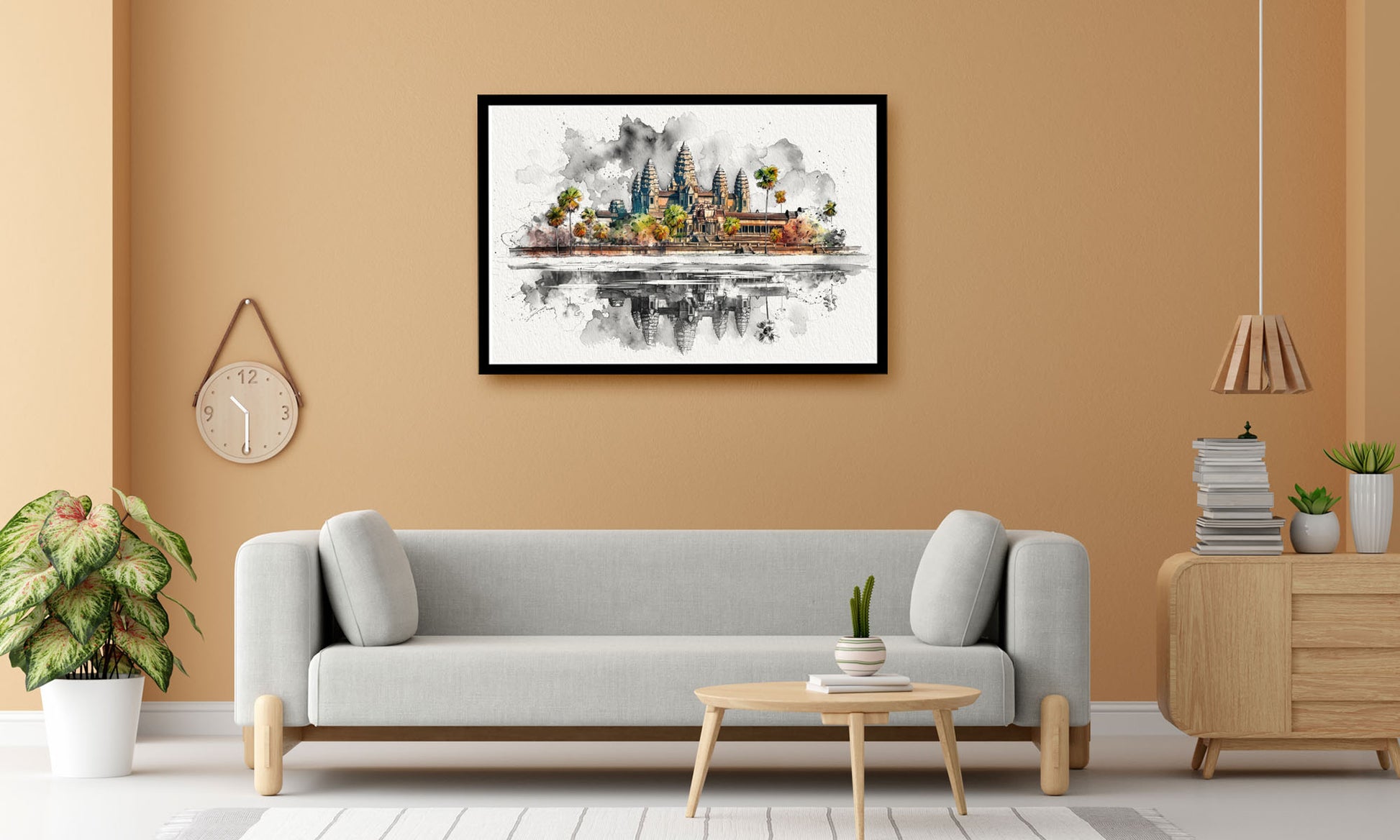 A framed watercolor painting of Angkor Wat and the surrounding temples in Cambodia, displayed on a warm beige wall above a modern light gray sofa in a styled living room.