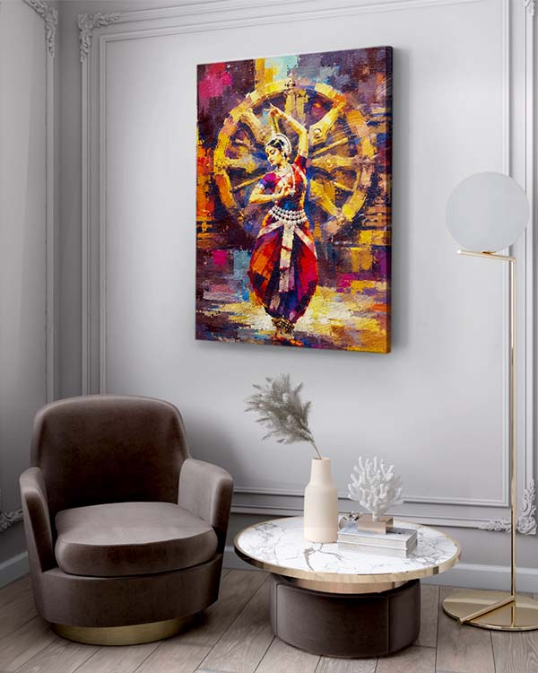 A colorful abstract canvas print of a dancer in front of a wheel hangs on a light gray wall in a modern living room setting with a brown armchair, marble coffee table, and floor lamp.