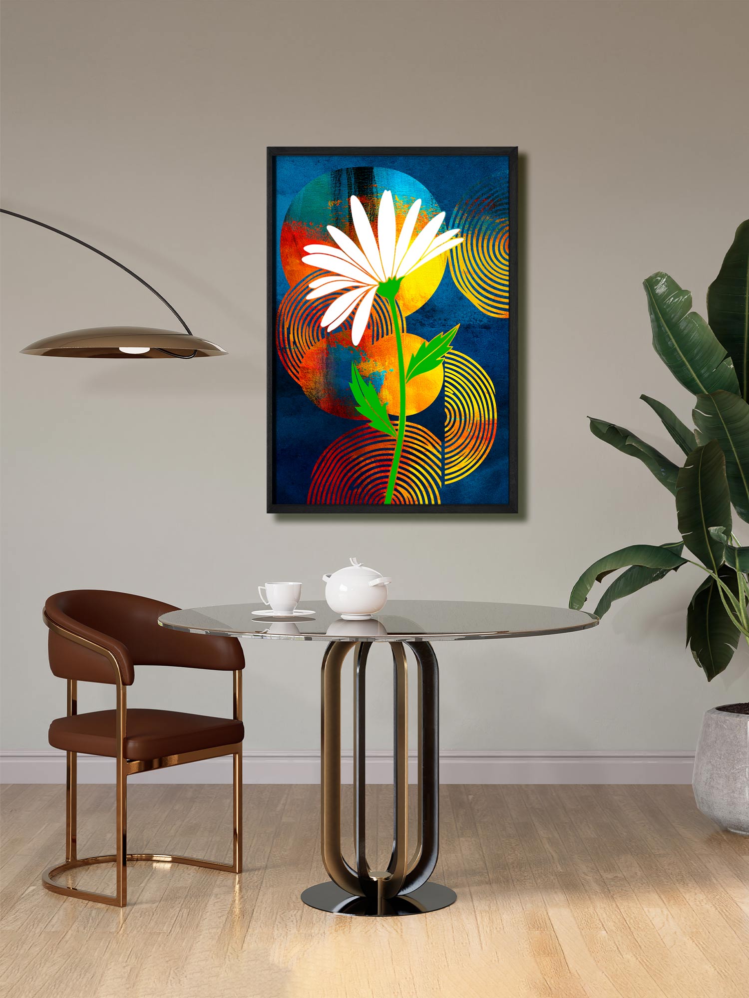 A framed abstract floral wall art print hangs above a round glass-top dining table in a modern room. The artwork features a large white flower with a green stem over a dark blue background with red, orange, and yellow circular patterns.