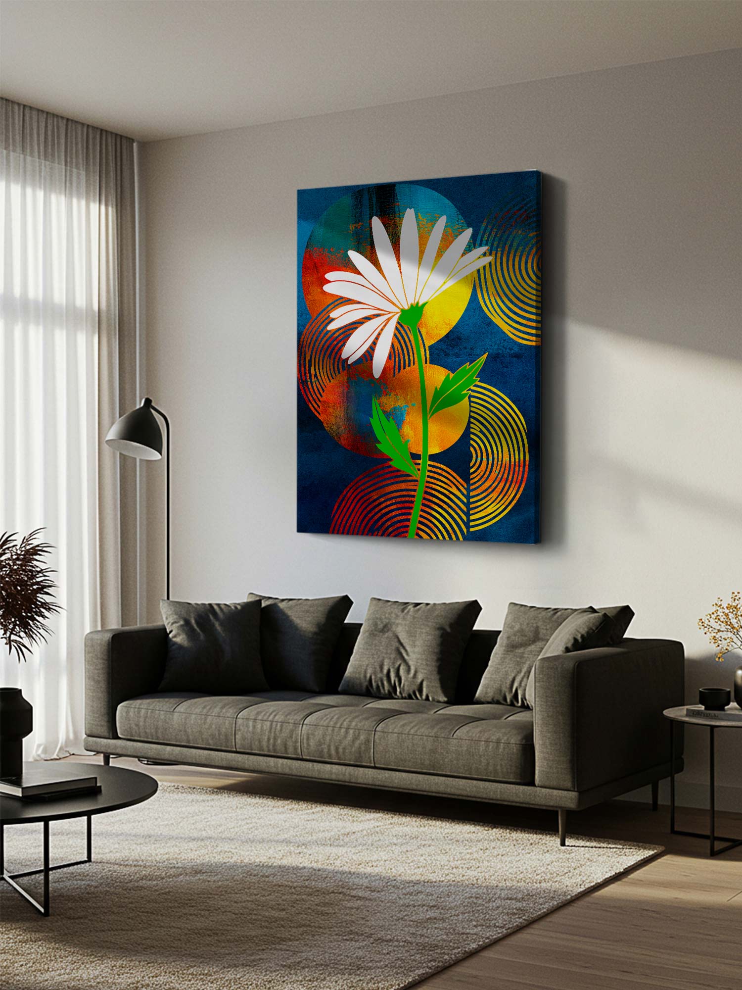A colorful abstract floral canvas print featuring a white daisy on a dark blue background with yellow, orange, and green accents, displayed on a light gray wall above a modern gray sofa in a styled living room.