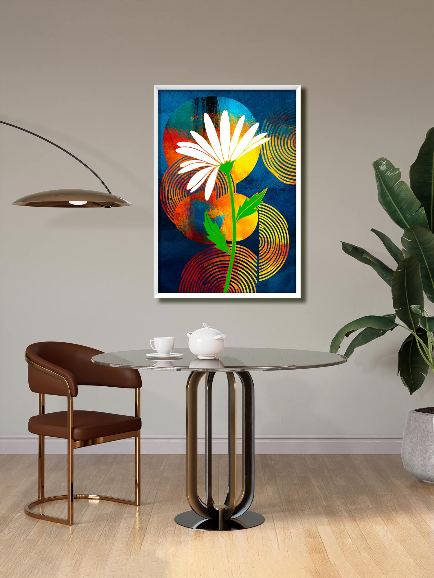 A framed abstract floral wall art print hangs above a round glass-top dining table in a modern room. The artwork features a white daisy-like flower with a green stem over a dark blue background with orange, yellow, and red circular patterns.