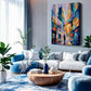 A modern living room with a large colorful abstract cityscape canvas print on the wall above a white sectional sofa with blue cushions, a blue rug, and potted plants.