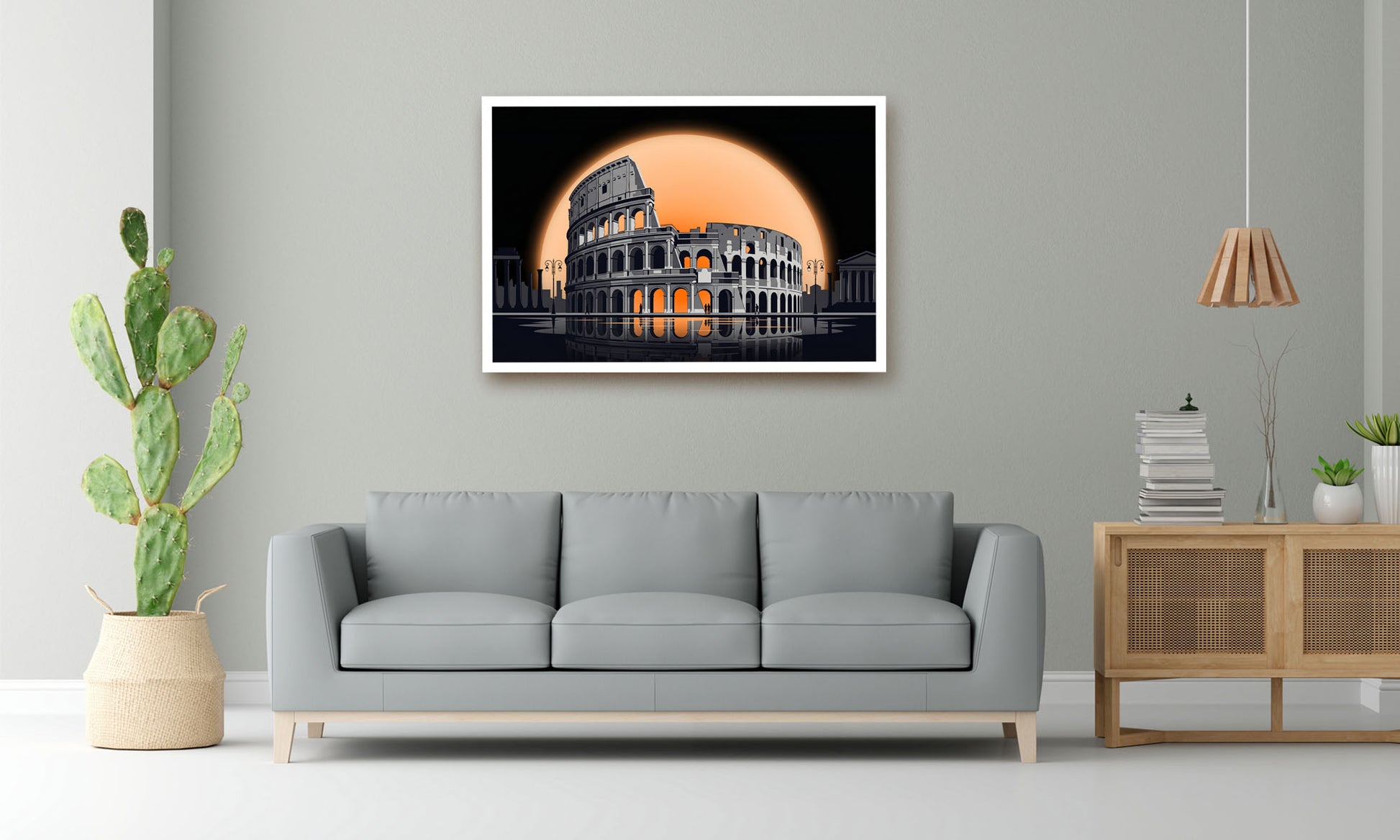 A framed wall art print depicting the Colosseum in Rome under a large orange moon, displayed on a light gray wall above a modern gray sofa in a styled living room.