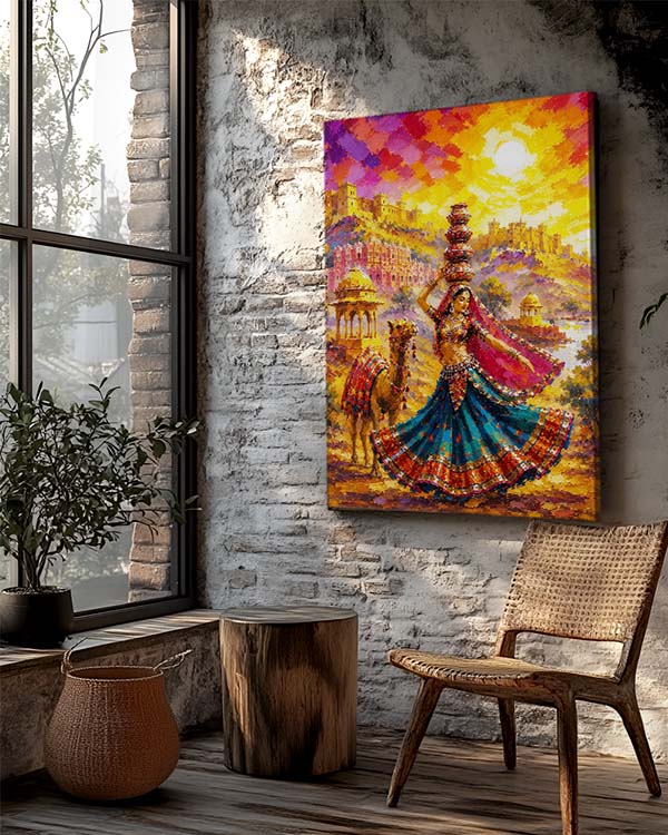 A colorful canvas wall art print depicting a vibrant folk dance scene with a woman in a blue and red skirt, camels, and a bright sunset sky, displayed on a rustic white brick wall in a styled room with a wooden chair, potted plant, and window.