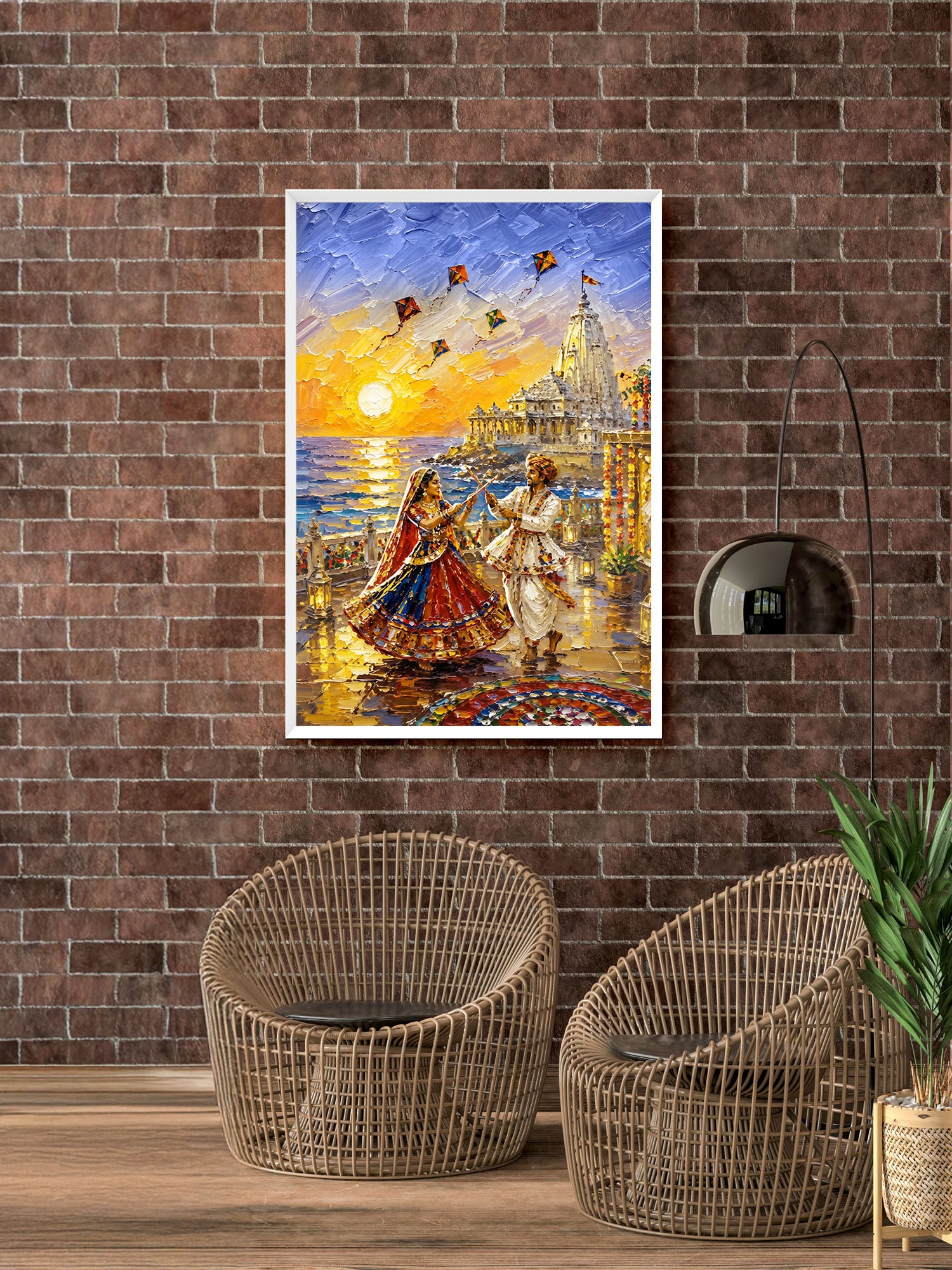A framed colorful painting of a couple dancing by the sea at sunset hangs on a brown brick wall above two woven wicker chairs in a styled room.