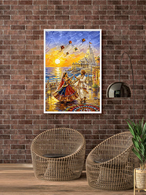 A framed colorful painting of a couple dancing by the sea at sunset hangs on a brown brick wall above two woven wicker chairs in a styled room.