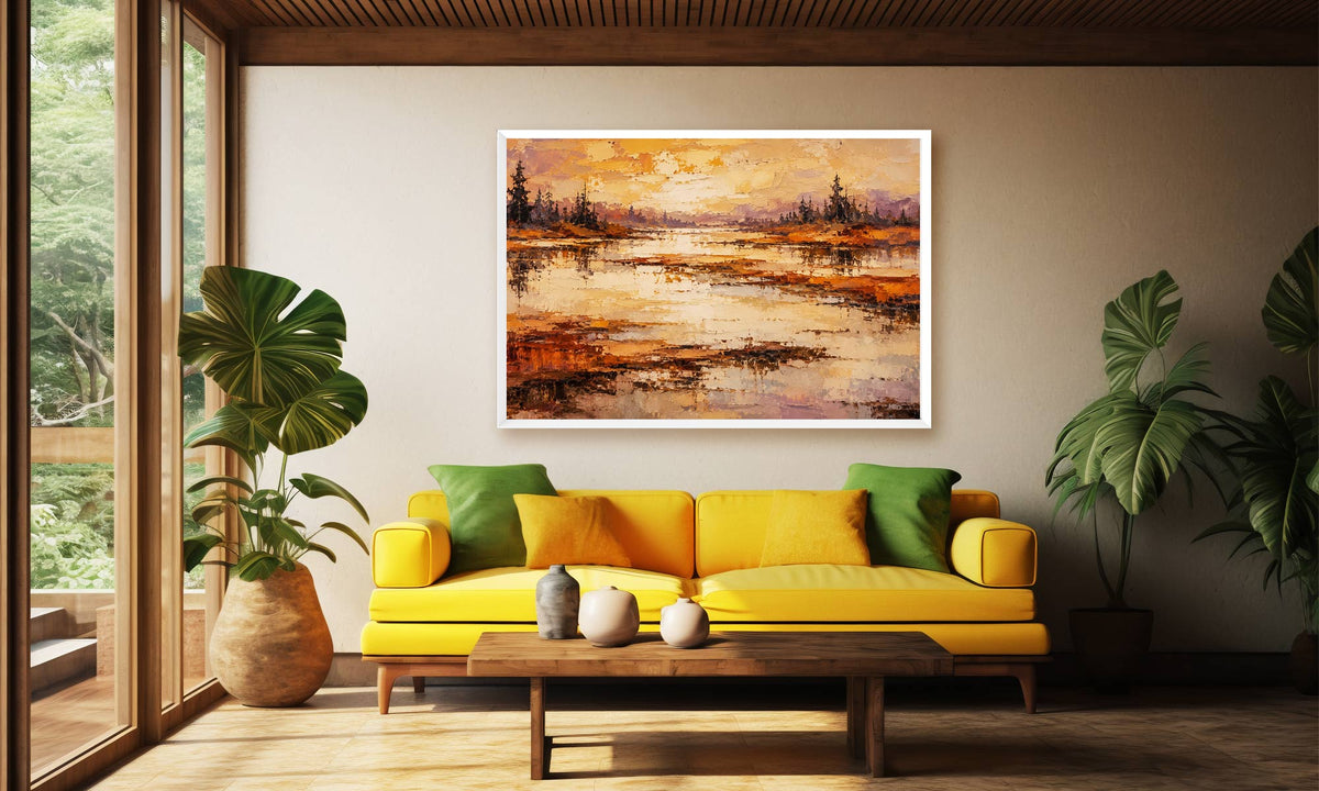 A framed landscape painting of a reflective lake at sunset hangs on a beige wall above a yellow sofa in a modern living room with green plants and a wooden coffee table.