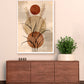Framed abstract art piece on a wall above a wooden cabinet with a plant.