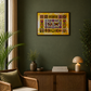 A framed colorful floral and geometric wall art print hangs on a dark green wall above a wooden sideboard in a styled living room with a wicker armchair, plants, and a lamp.