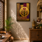 A framed wall art print featuring a stylized botanical design in gold, purple, black, and red, displayed in a warm, sunlit room with wooden furniture and a patterned rug.