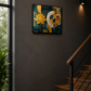 A framed abstract wall art piece featuring a yellow lotus flower and geometric shapes in blue, gold, and white, displayed on a dark grey wall in a modern interior with wooden stairs and a window.