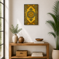 A framed wall art print featuring a golden-yellow and green ornate geometric pattern, displayed in a styled room above a wooden console table with plants and books.