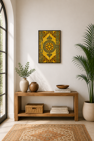 A framed wall art print featuring a golden-yellow and green ornate geometric pattern, displayed in a styled room above a wooden console table with plants and books.