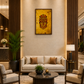 A modern living room interior featuring a beige sofa, two matching armchairs, a round dark coffee table, and a large framed gold wall art piece with a stylized face design, set against a warm beige wall with decorative wood slat columns.