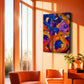 Abstract canvas wall art with swirling purple, blue, orange, and yellow brushstrokes displayed in a modern living room with orange walls and two orange armchairs.