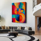 A large vertical canvas print featuring a vibrant, colorful abstract geometric design, displayed on a white wall in a modern living room setting above a gray sectional sofa.