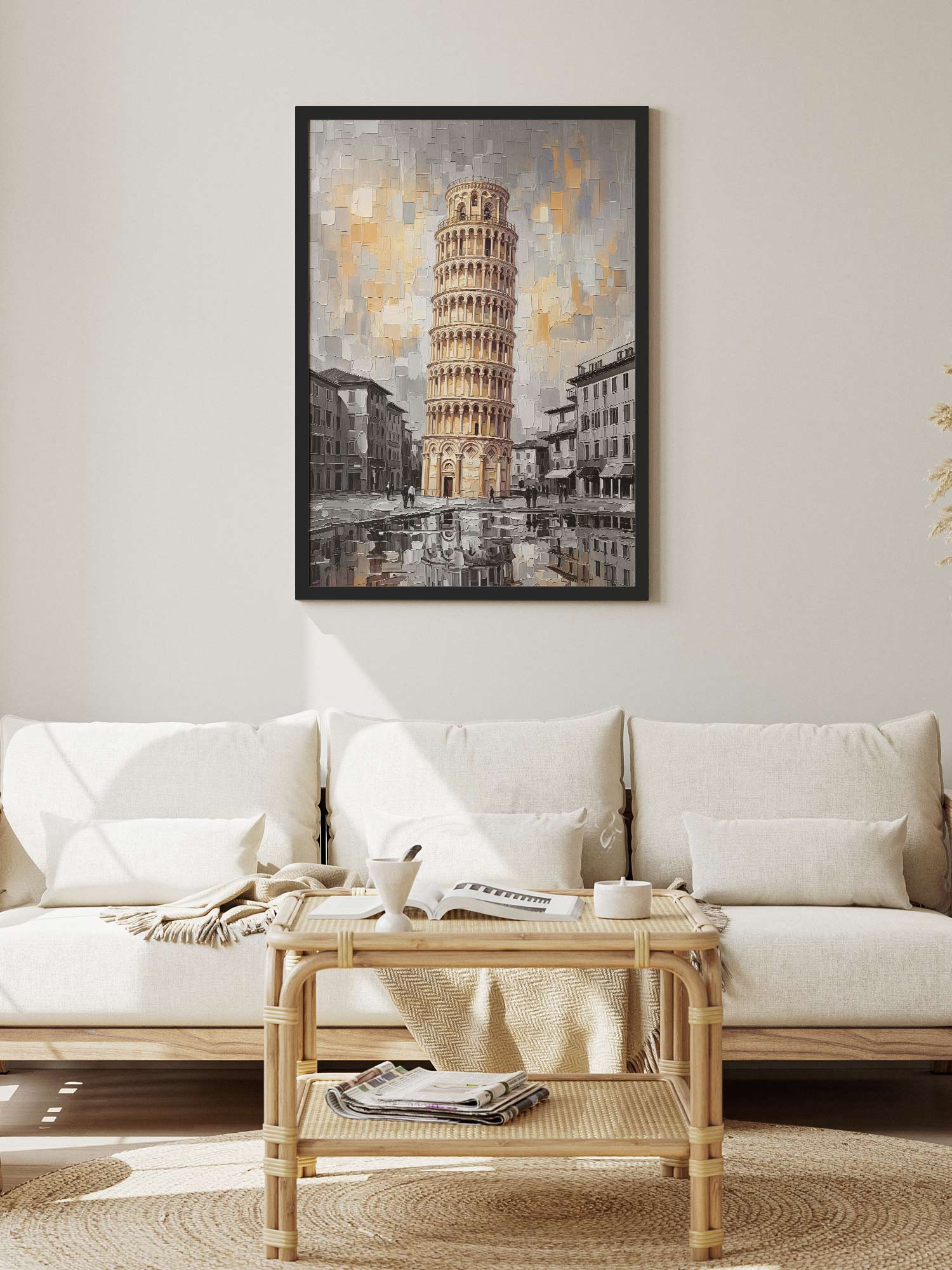 A framed art print of the Leaning Tower of Pisa hangs on a light beige wall above a white sofa in a modern, sunlit living room.