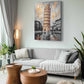 A rectangular canvas wall art print depicting the Leaning Tower of Pisa in an urban scene, styled in a modern living room above a light gray sofa.