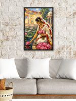A framed vertical canvas art print depicting a woman in a white saree with pink lotus flowers, hanging on a white brick wall above a gray sofa with white pillows.