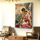A vertical canvas wall art print depicting a woman in a white sari among pink lotus flowers, displayed on a cream wall in a styled living room setting with two leather armchairs and a wooden trunk.