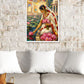 A framed vertical art print depicting a woman in a white sari with pink lotus flowers, hanging on a white brick wall above a gray sofa with white pillows.