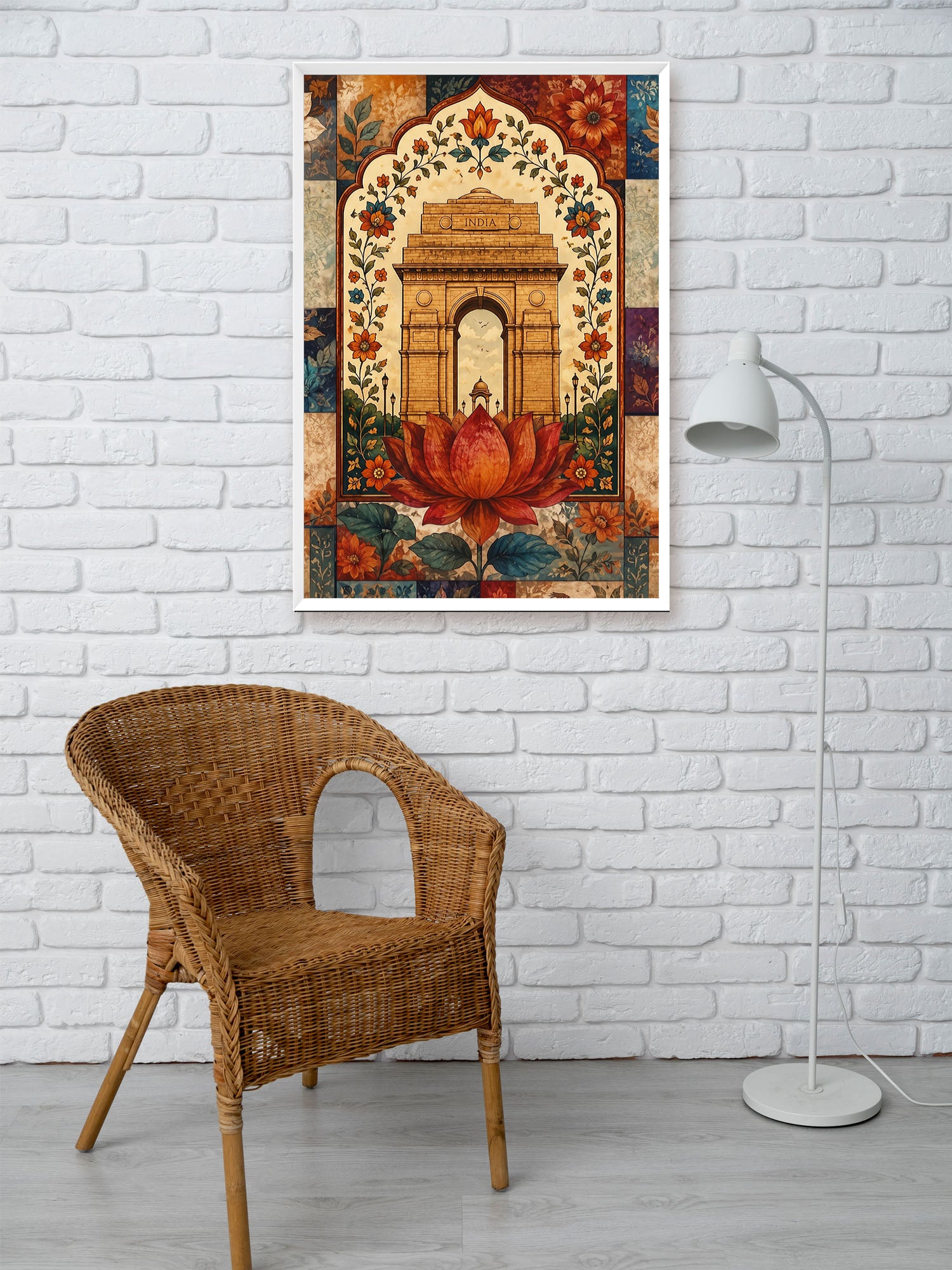 A framed art print featuring a traditional Indian architectural archway with a large red lotus flower, displayed on a white brick wall above a wicker chair and next to a white floor lamp.