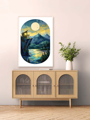 Framed artwork of a mountain landscape with a cabin on a wall above a wooden cabinet.