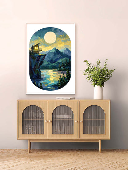 Framed artwork of a mountain landscape with a cabin on a wall above a wooden cabinet.