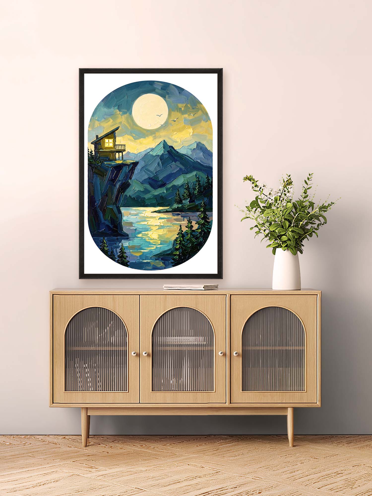 Framed artwork of a mountain landscape above a wooden cabinet with glass doors.