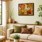A framed abstract painting with warm orange, yellow, and red tones hangs on a light beige wall above a cream sofa in a styled living room with woven decor, plants, and a wicker pendant light.