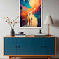 A colorful framed wall art print hangs above a mid-century modern credenza in a styled room. The artwork features an abstract scene with a large glowing moon, a winding path, and silhouetted figures, rendered in blue, orange, yellow, and red tones.