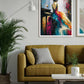 A framed abstract painting of a woman in a flowing multicolored dress hanging on a light gray wall above a mustard yellow sofa in a modern living room setting.