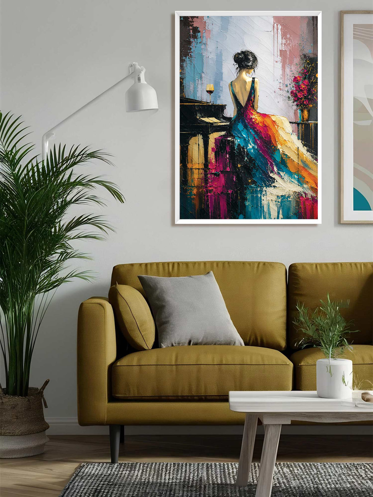 A framed abstract painting of a woman in a flowing multicolored dress hanging on a light gray wall above a mustard yellow sofa in a modern living room setting.