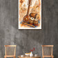 A framed wall art print featuring traditional Indian musical instruments, including a lute, tabla, and flute, displayed on a textured gray wall above a small round wooden table with two wooden chairs.