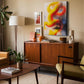 Ribbon Rhythm contemporary abstract canvas wall art featuring flowing golden yellow, orange and red ribbon forms with a serene landscape and trees