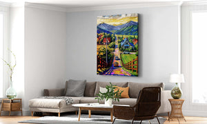 Countryside mountain canvas wall art featuring a colorful village road, charming homes, green fields, and majestic mountain scenery.
