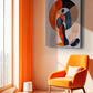 Abstract wall art featuring two stylized human figures in orange, navy, black, beige, and gray, displayed on a beige wall in a modern room with an orange armchair, orange curtains, and a window.