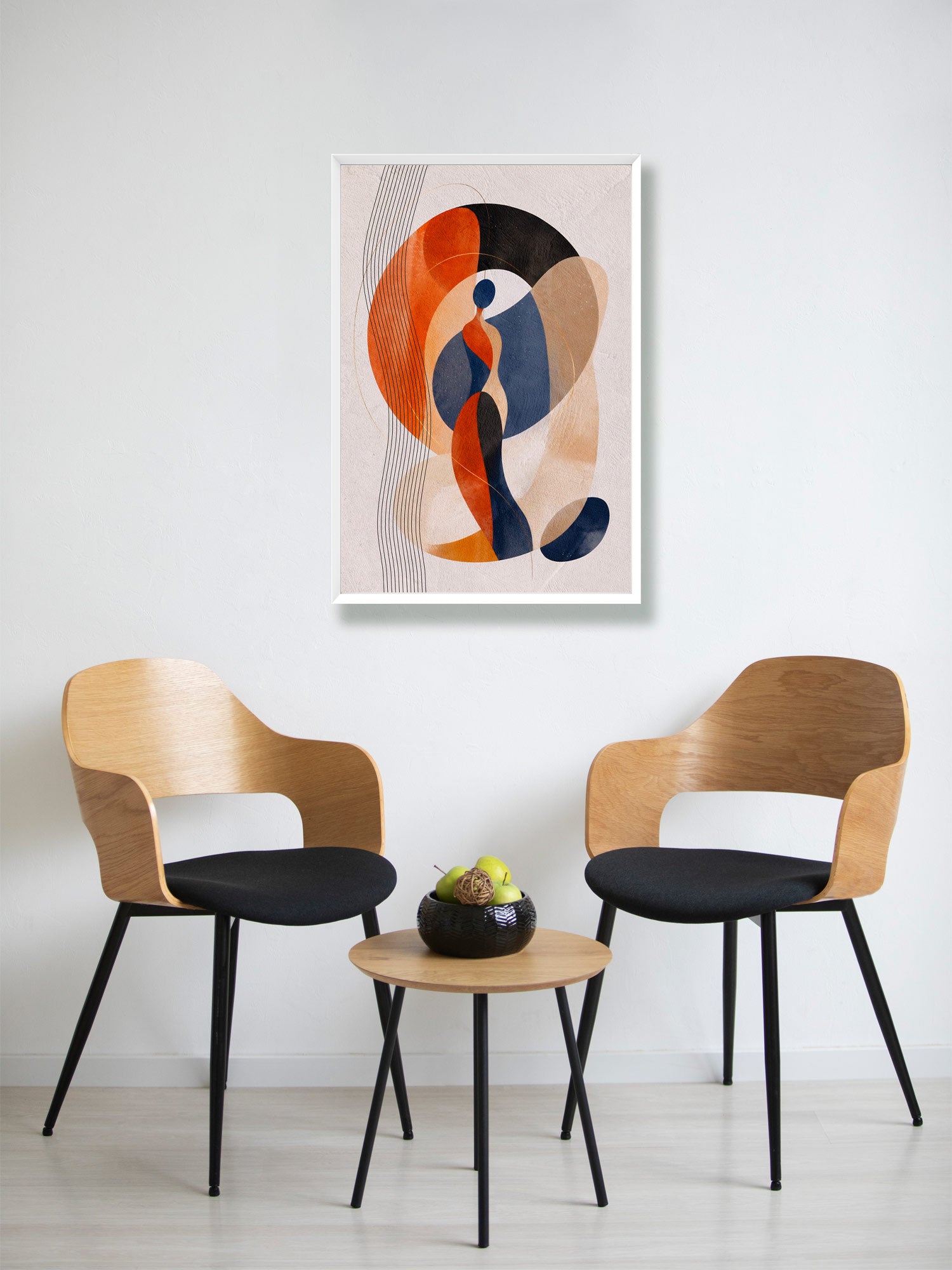 A framed abstract art print featuring orange, navy, beige, and black organic shapes, displayed on a white wall above a small wooden table with two modern wooden chairs.