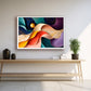 A colorful abstract wall art print with flowing curved shapes in blue, purple, orange, yellow, and red, displayed in a white frame on a light gray wall above a wooden console table in a modern interior setting.