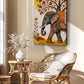 A vertical canvas wall art print featuring a decorated elephant beneath a tree with autumn leaves, styled in a warm, sunlit room next to a wicker chair and side table.