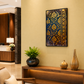 A framed vertical art print featuring an intricate navy blue and gold floral damask pattern, displayed on a warm beige wall in a modern, stylish living room setting.