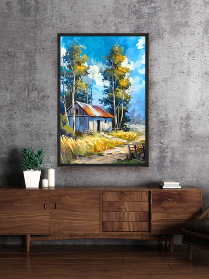Framed painting of a cabin in the woods above a wooden console table.