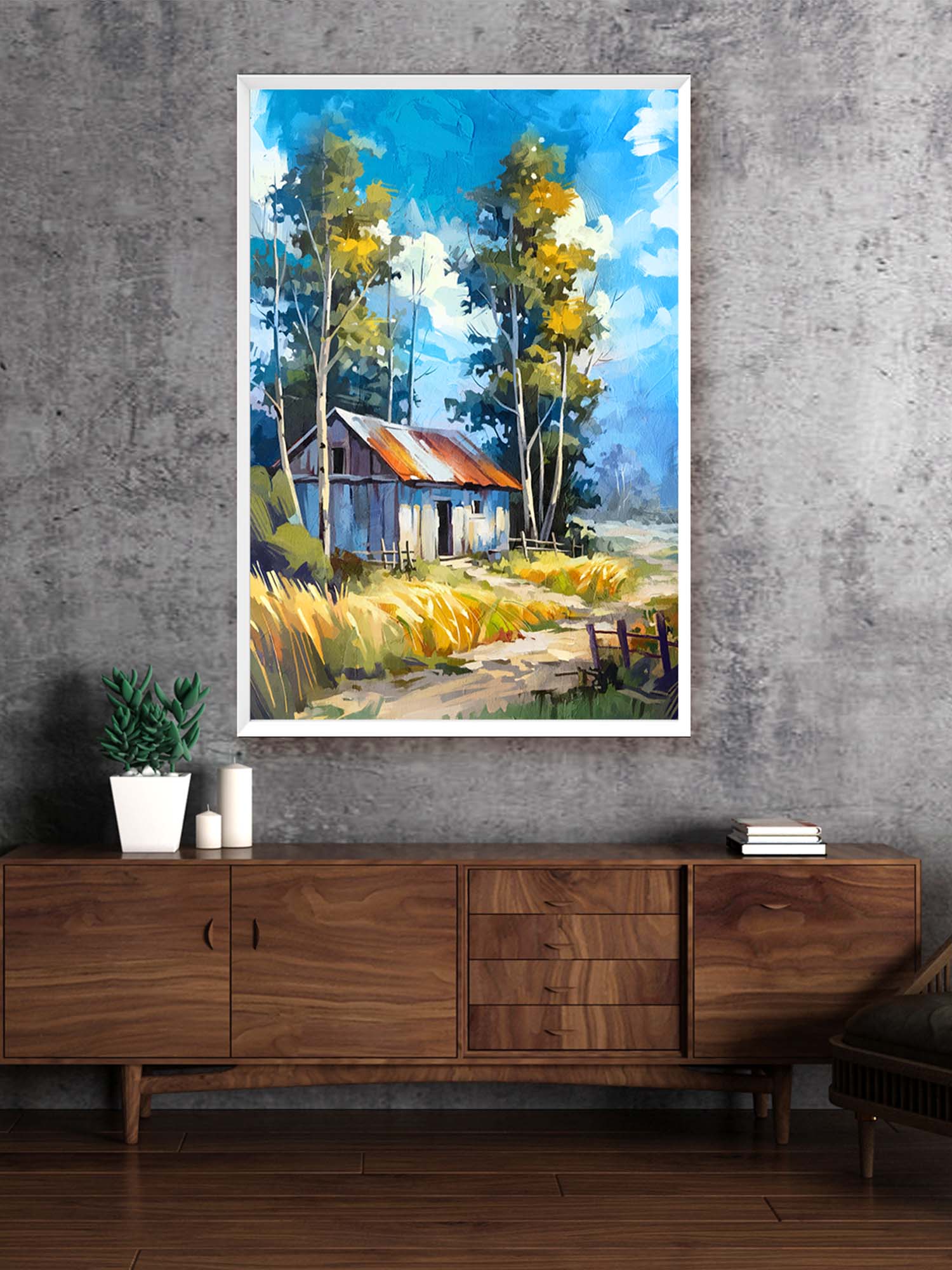 Framed painting of a rustic cabin in nature above a wooden cabinet.