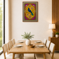 A framed art print featuring a vibrant peacock illustration in gold, purple, and blue, displayed on a beige wall in a modern dining room setting above a wooden dining table and chairs.