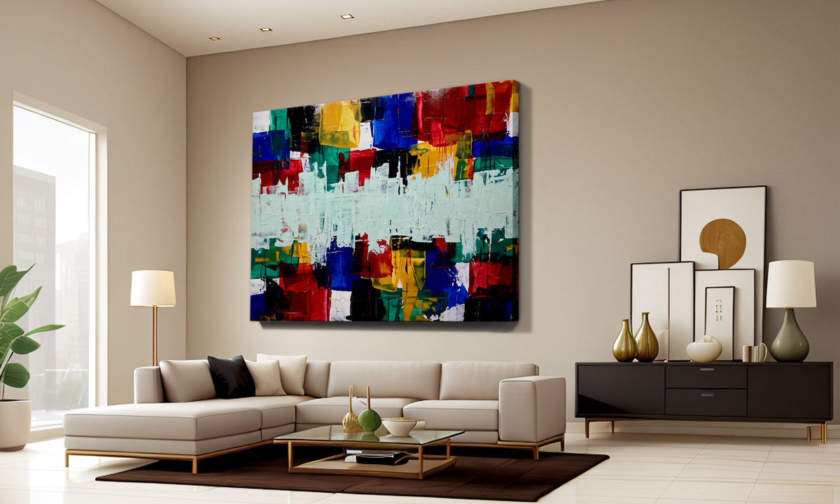 A large abstract canvas wall art print with vibrant multicolor brushstrokes is displayed in a modern living room setting above a beige sectional sofa.