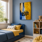A styled children's bedroom featuring a prominent vertical gold canvas wall art print with a yellow and blue waterfall and a black car, mounted on a blue wall above a bed with blue and yellow bedding.