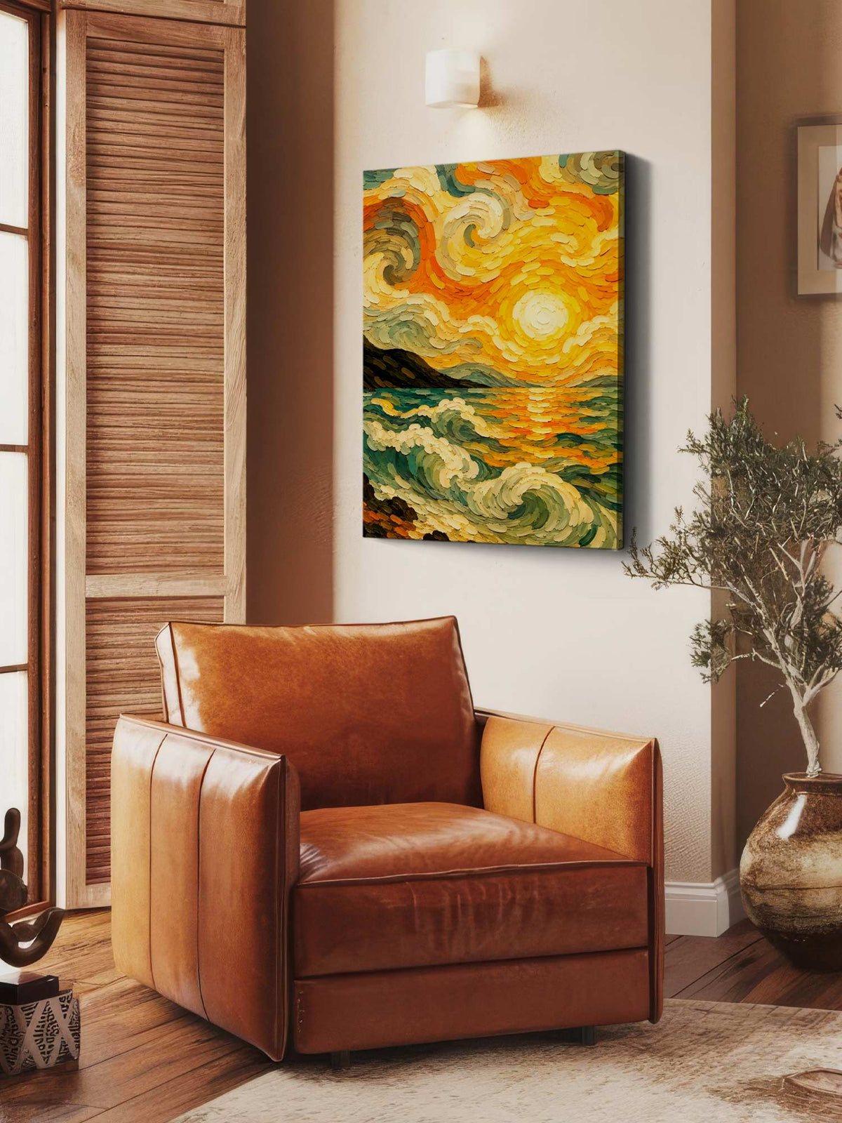 A square canvas wall art print featuring a swirling, impressionistic sunset landscape in yellow, orange, green, and cream tones, displayed on a beige wall above a brown leather armchair in a styled room.